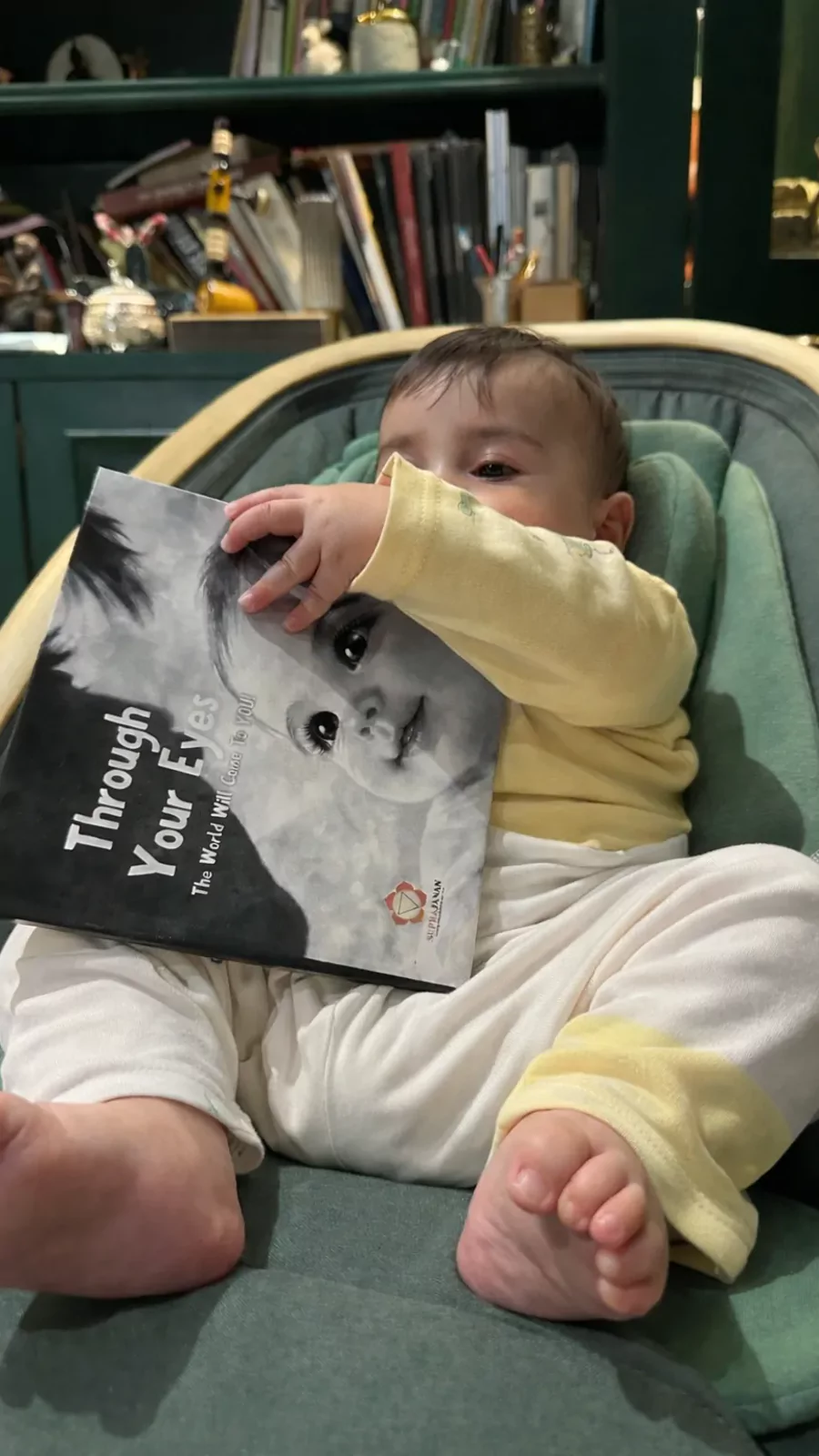 Baby holding the Through Your Eyes high-contrast story book from the Drishti Kit
