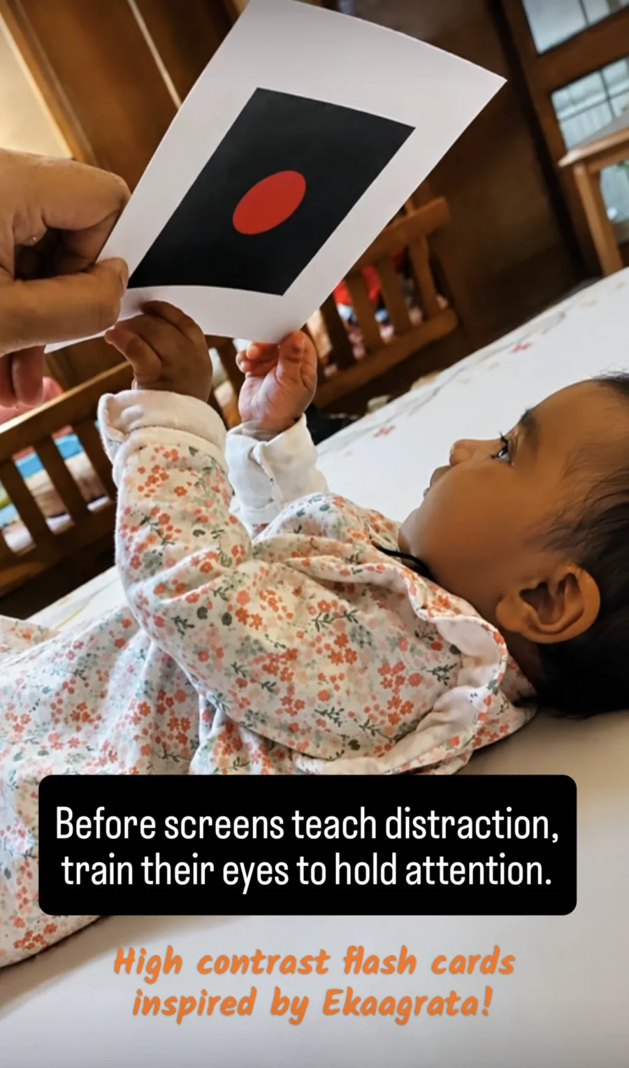 Baby reaching for a red-dot focus card from the Drishti Kit
