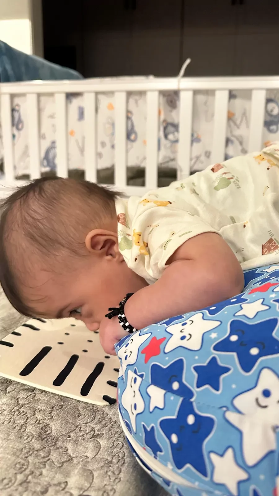 Baby on a tummy-time pillow beside a high-contrast fabric card